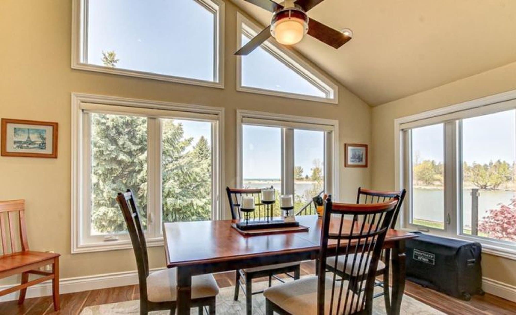 Bright dining room featuring a wooden table, chairs, and large windows with scenic waterfront views.