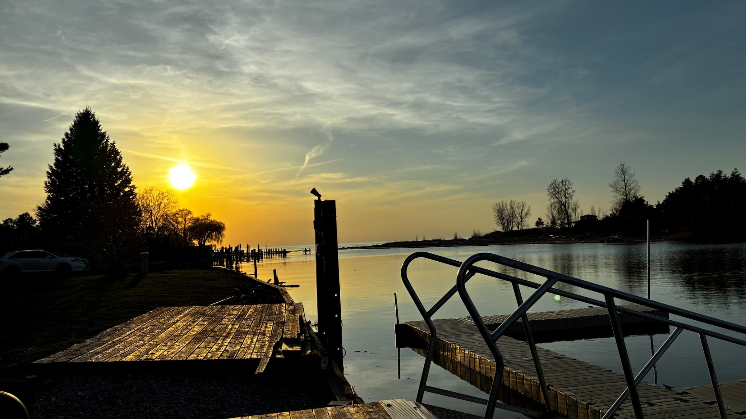 Golden sunset over a calm lake with wooden docks and metal railings in the foreground.