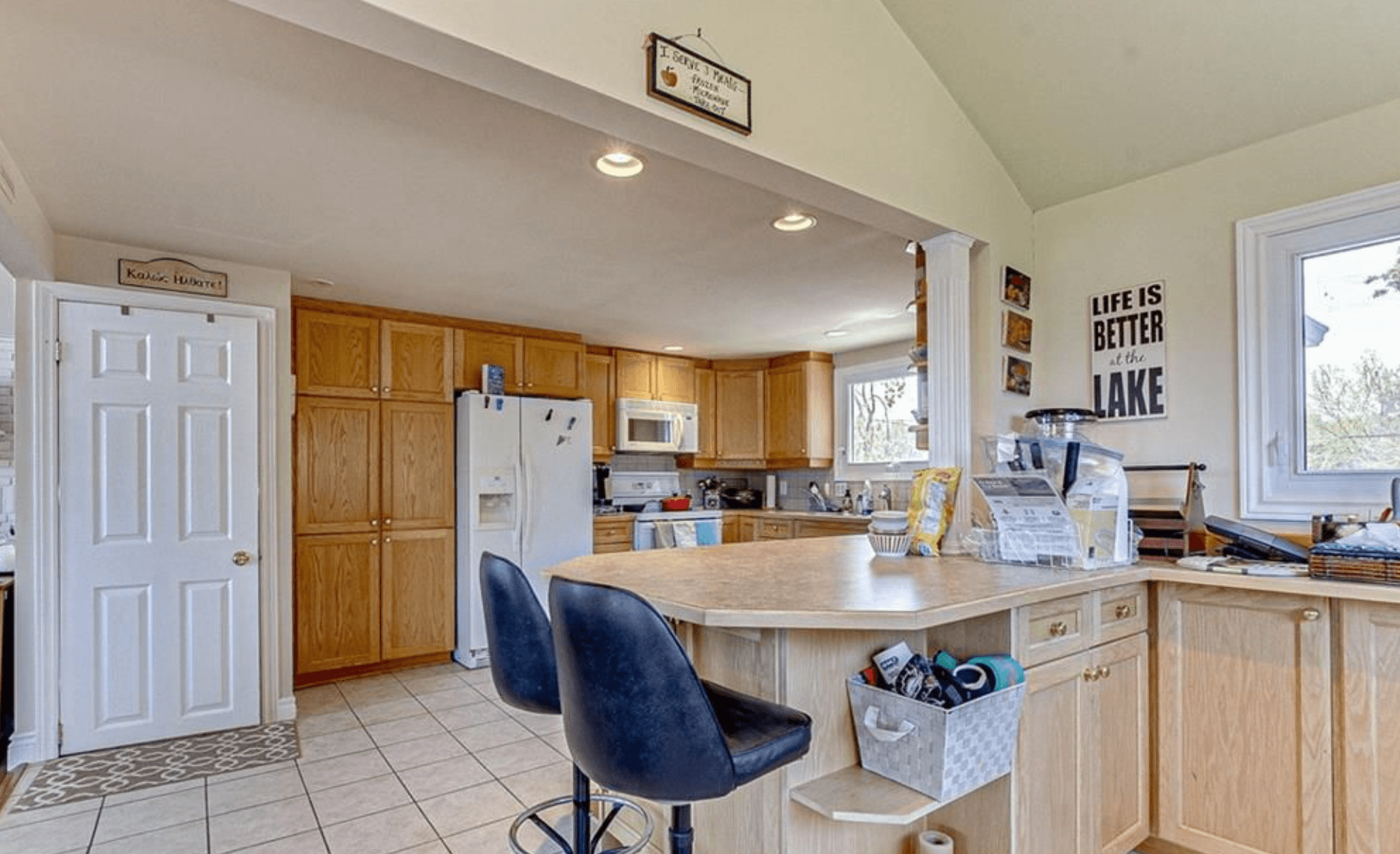 Bright kitchen featuring oak cabinets, white appliances, and a large island with black stools.